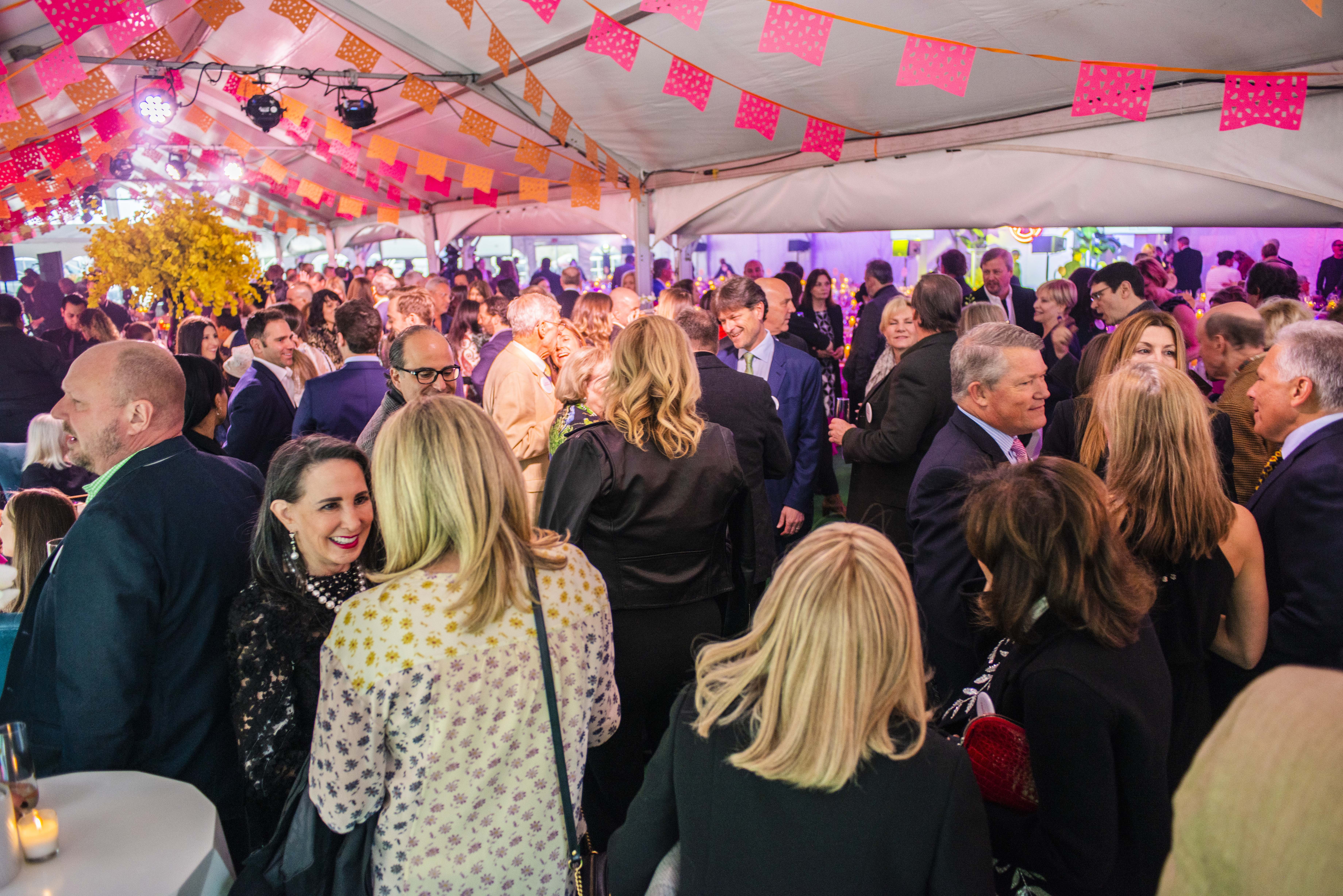 people stand under tent socializing at STUDIO fundraiser