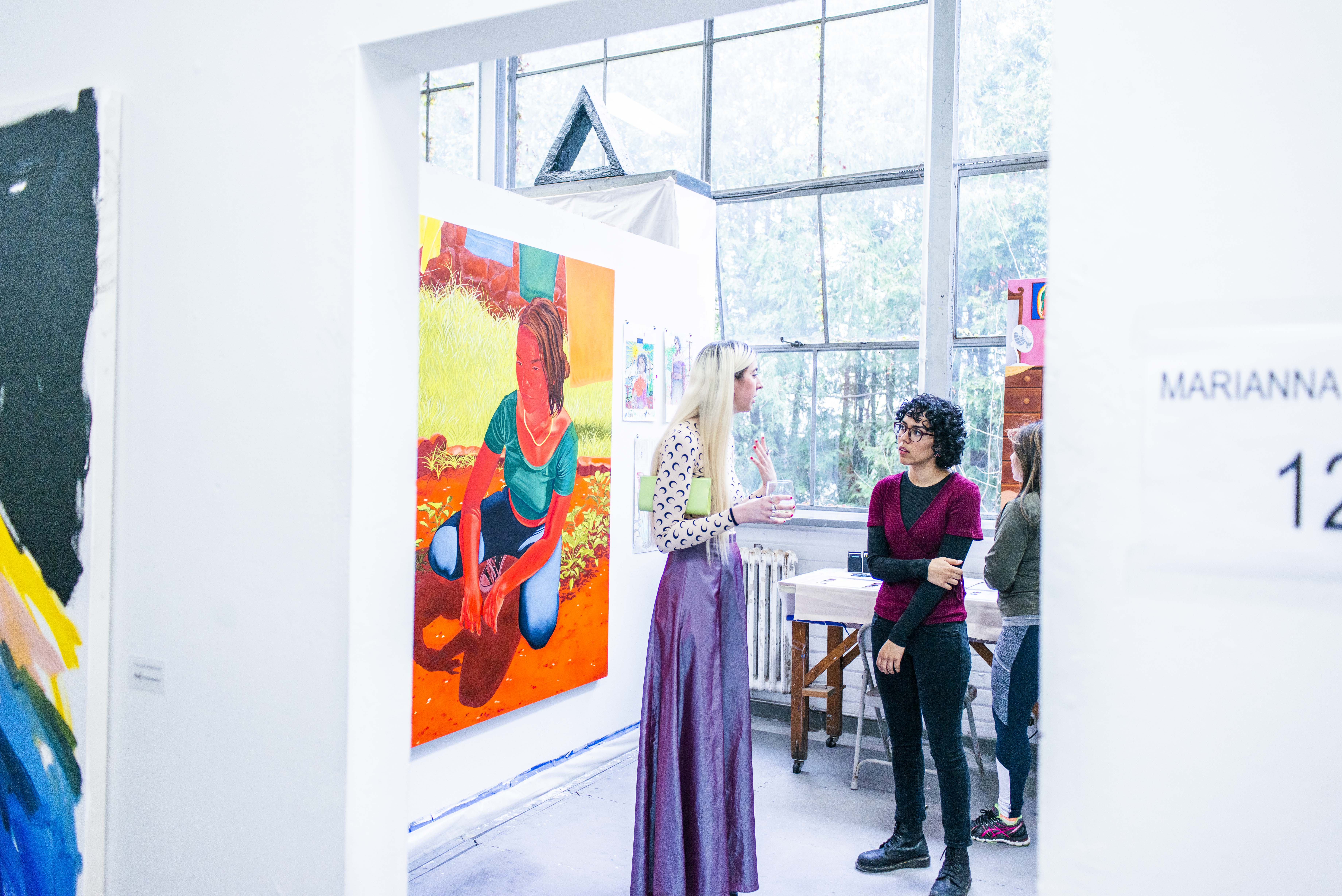 two women speaking near painting of a woman