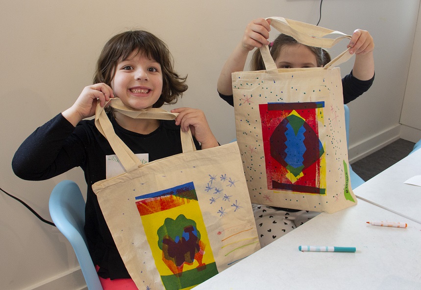 two children with screen printed tote bags smile at camera