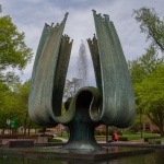 A large organic-shaped sculpture and fountain in a treed park area