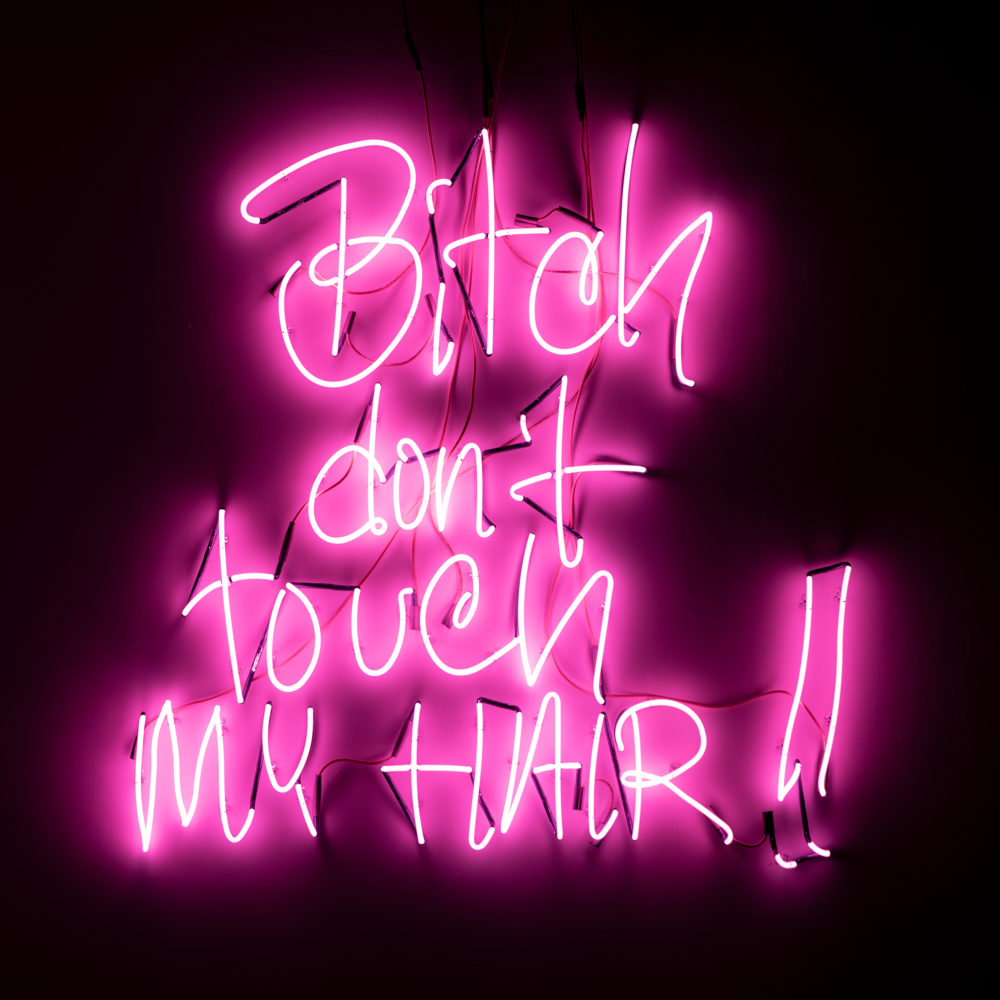 The words “Bitch Don't Touch My Hair” in Tiff Massey’s handwriting are rendered in pink neon and mounted on the wall.