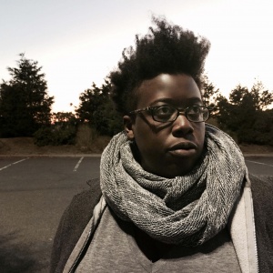 portait of woman wearing scarf, parking spaces and trees in the background.