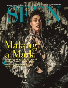A magazine cover featuring a person with curly hair and large tear-drop shaped earrings in front of a circular abstract painting. The title of the magazine in teal reads "SEEN", the main headline in yellow reads, "Making a Mark."